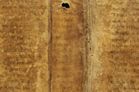 The original, pierced sewing holes of the codex are visible in the opening of the binding parchment